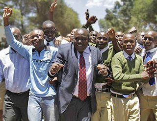 Kenya's number 1 student, Tom Wanderi King’ori (left), and principal Mr. David Gideon Kariuki, surrounded by other students from Alliance High School celebrate the school's outstanding performance.