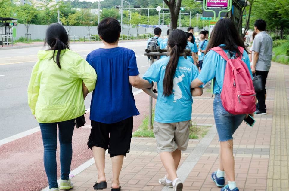 Volunteers taking their "grandmother" out for a walk on the town.