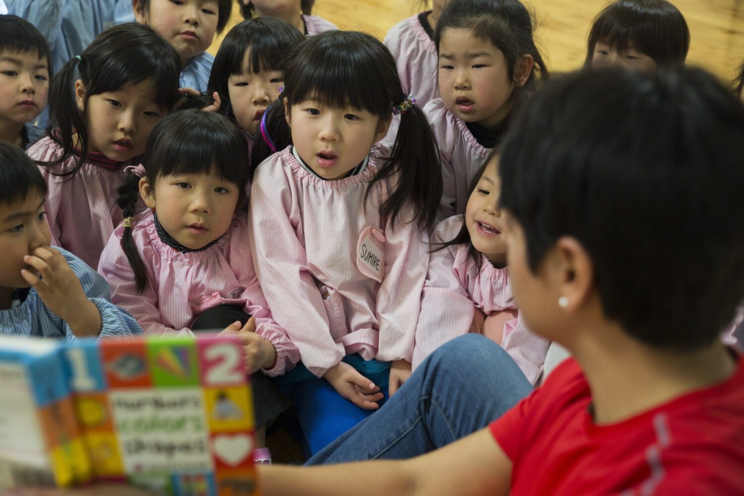 Japanese preschool students listening to the teacher reading a book