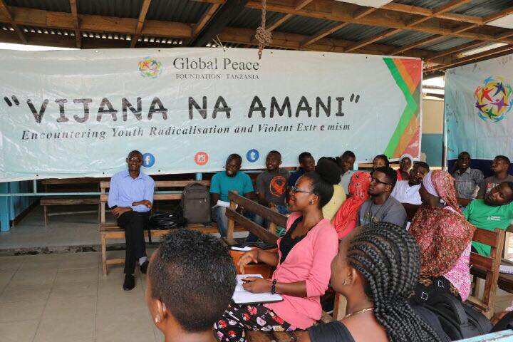 Young leaders sit by banner 'Youth for Peace' in Tanzania workshop